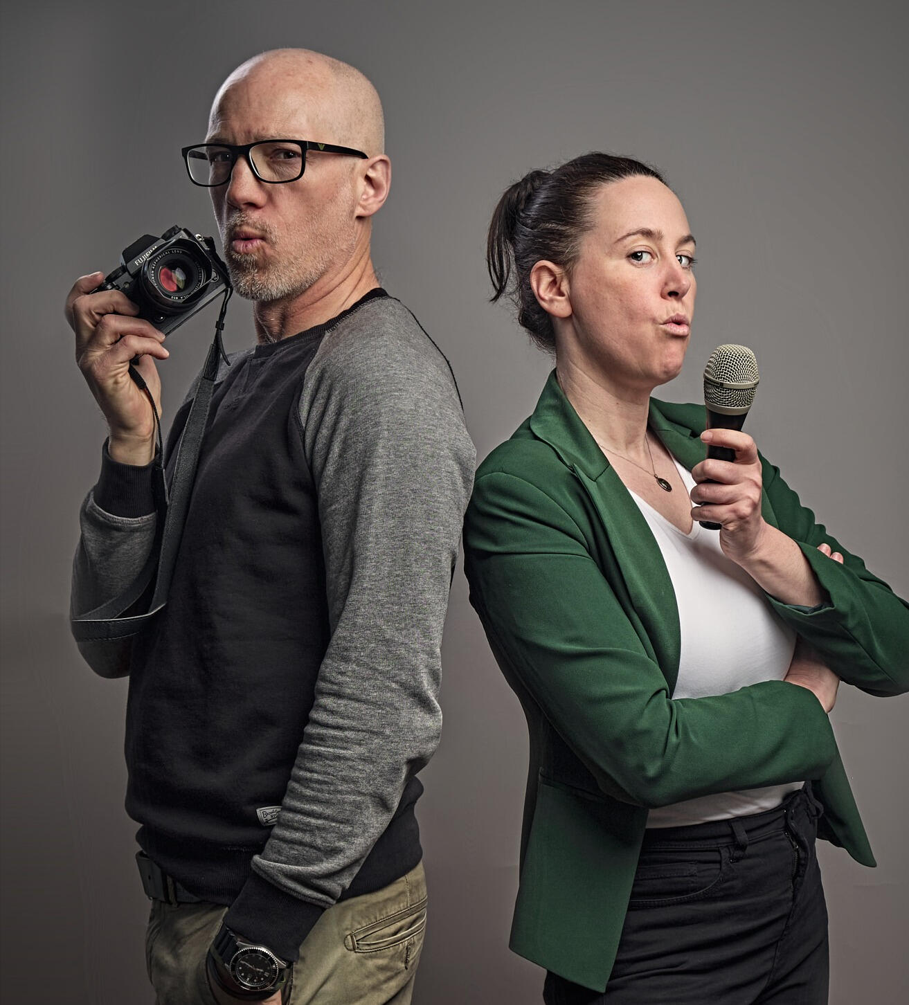 Alex Harris and Sarah Martens blowing imaginary smoke from their camera and microphone as if from smoking guns.