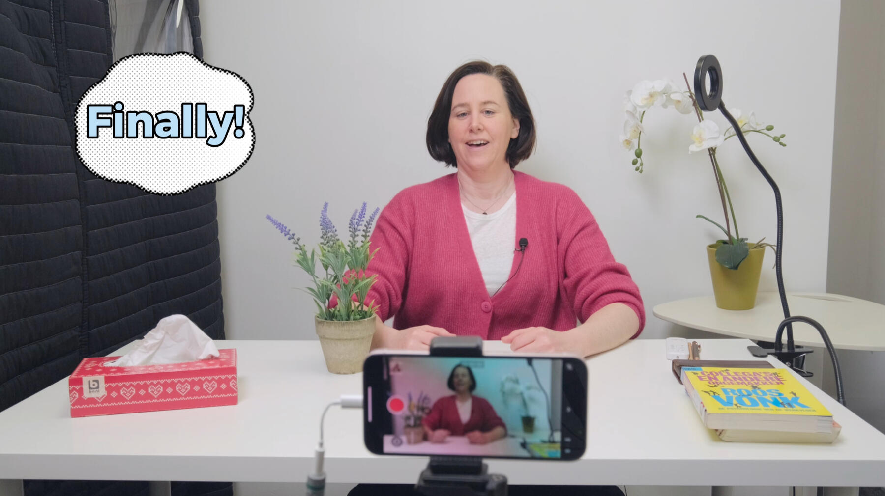 Sarah Martens sitting behind a smartphone camera looking relieved and saying "finally!"